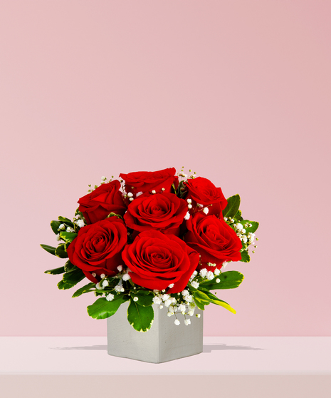 A timeless arrangement of red roses with baby’s breath and greenery in a white ceramic vase, handcrafted by Billy Heroman’s Florist in Baton Rouge, LA.