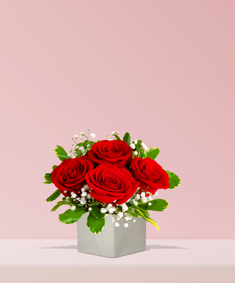 A timeless arrangement of red roses with baby’s breath and greenery in a white ceramic vase, handcrafted by Billy Heroman’s Florist in Baton Rouge, LA.