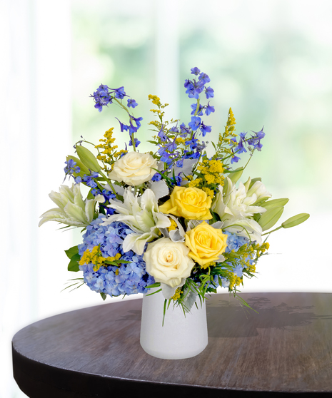 Sassy Sapphire flower arrangement with blue delphiniums, white lilies, and seasonal blooms