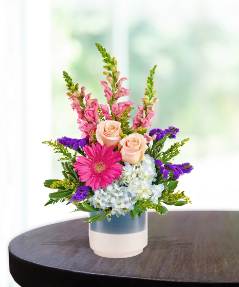 pink flowers and roses in a cream vase