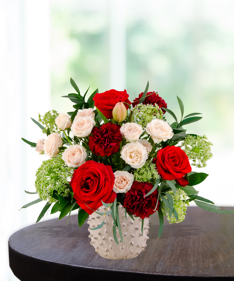 Garnet N' Roses floral arrangement with red roses, fuchsia garden roses, blush spray roses, and burgundy snapdragons in a textured white ceramic vase.