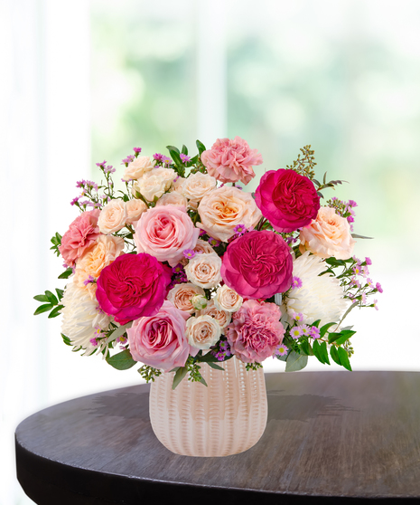 Blush Parlor floral arrangement featuring pink garden roses, spray roses, white chrysanthemums, carnations, and aster in a textured ceramic vase.