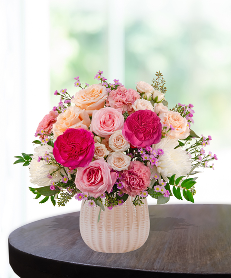 Blush Parlor floral arrangement featuring pink garden roses, spray roses, white chrysanthemums, carnations, and aster in a textured ceramic vase.