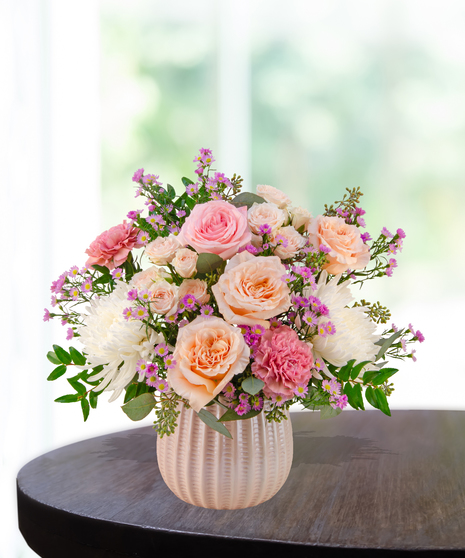 Blush Parlor floral arrangement featuring pink garden roses, spray roses, white chrysanthemums, carnations, and aster in a textured ceramic vase.