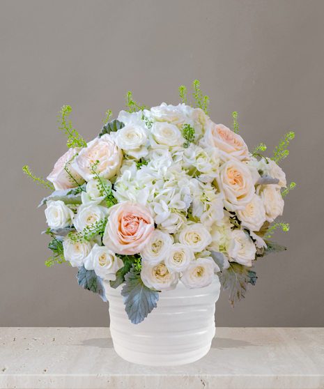 Billy Heroman's Signature Collection white and blush flower arrangement with roses, hydrangeas, and greenery in a textured white vase