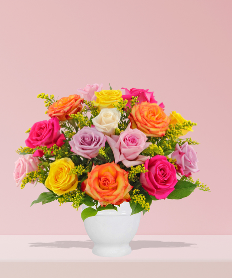 A vibrant multicolored rose bouquet with solidago accents, arranged in a white ceramic vase by Billy Heroman’s Florist in Baton Rouge, LA.