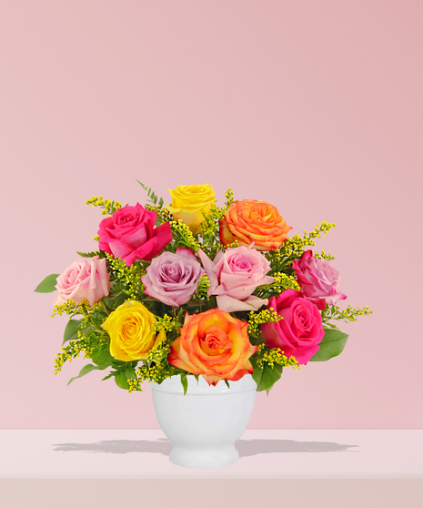 A vibrant multicolored rose bouquet with solidago accents, arranged in a white ceramic vase by Billy Heroman’s Florist in Baton Rouge, LA.